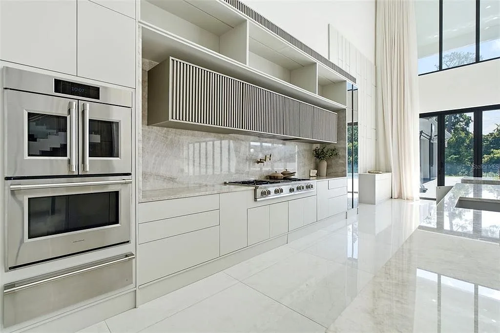Kitchen range wall with stainless double ovens, a stone backsplash, and a fluted range hood.