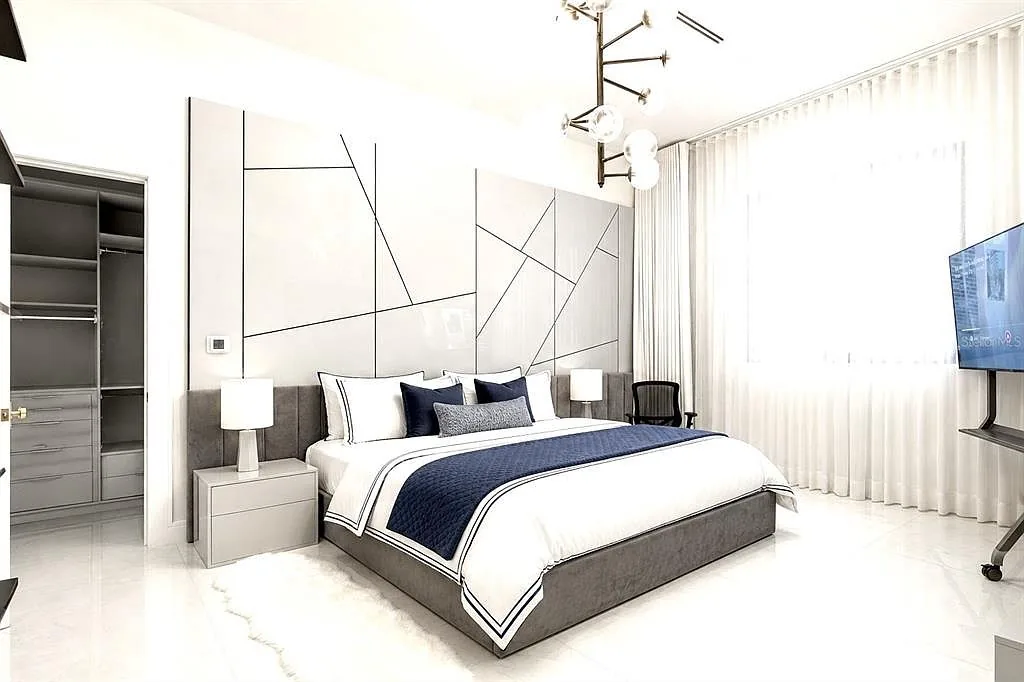 Bedroom with a white geometric headboard wall, a gray upholstered bed, and a globe chandelier.
