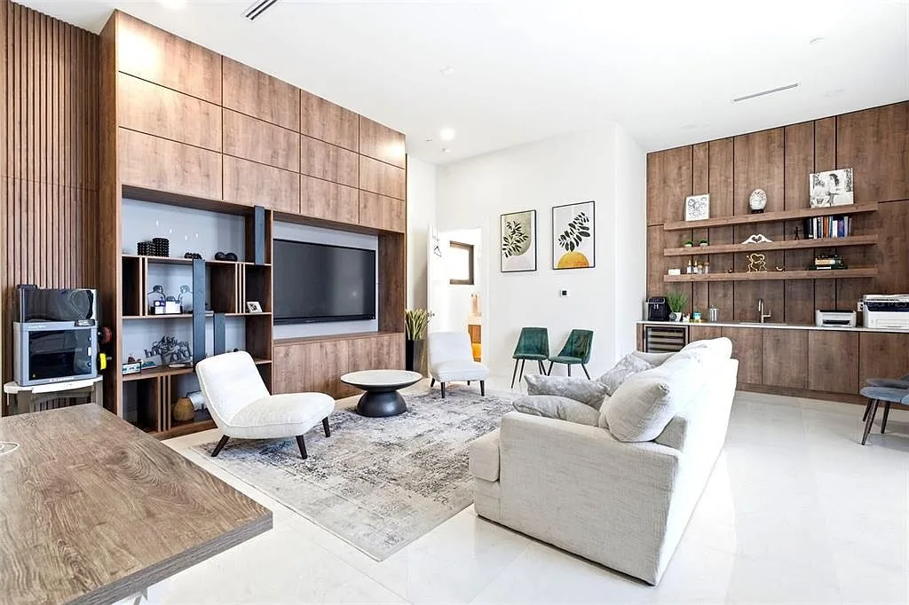 Family room with walnut built-ins around a TV, a white sofa, and a wood-paneled coffee bar with open shelves.