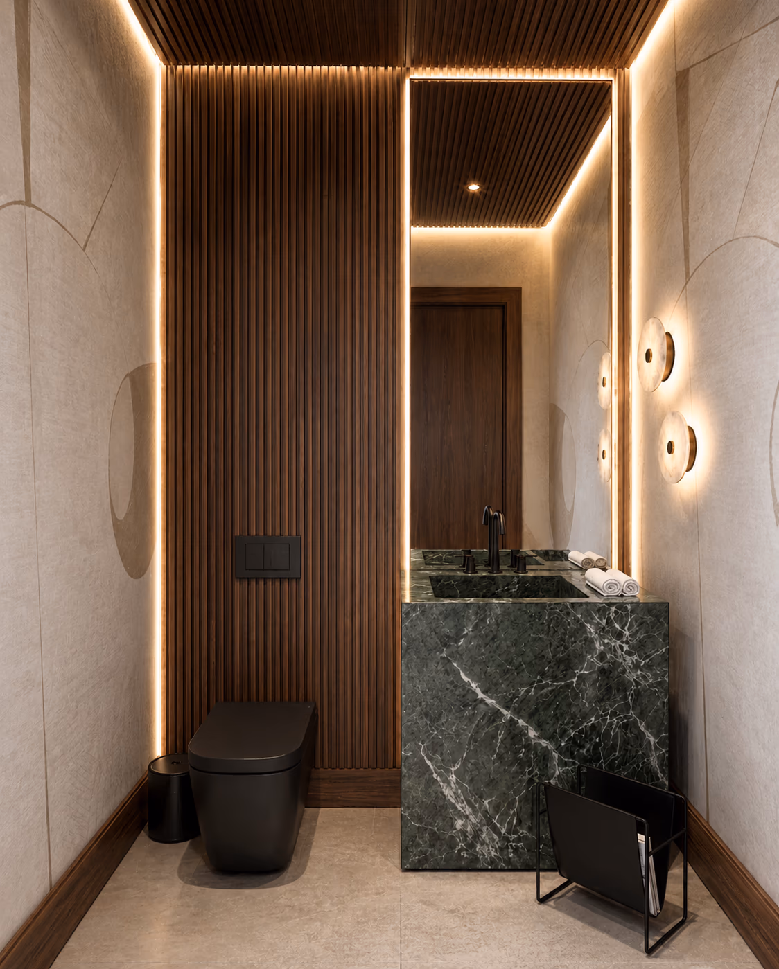 Powder room with a green marble vanity, a black wall-hung toilet, a fluted walnut panel, and round wall sconces.