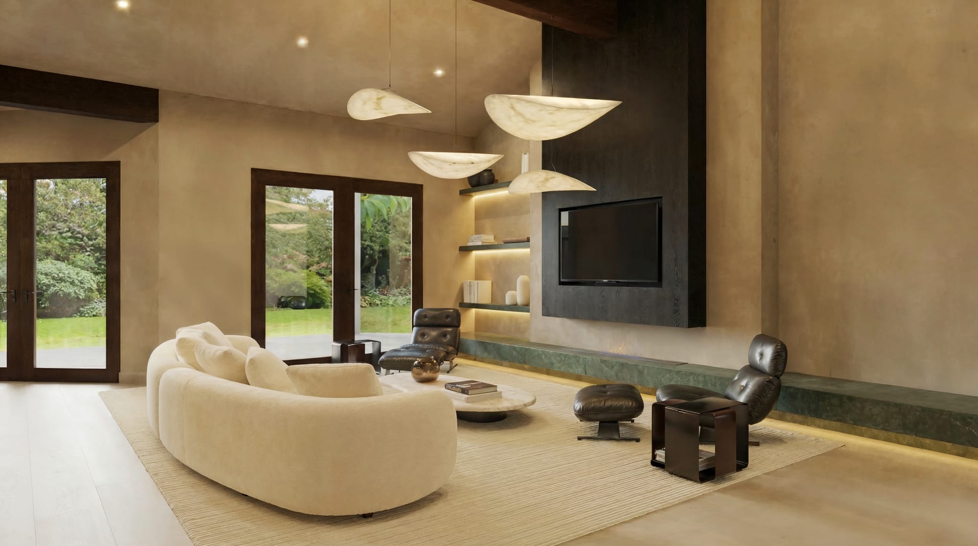 Living room with a curved cream sofa, leather lounge chairs, floating shelves, and a dark wood media wall under sculptural pendant lights.